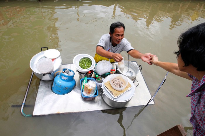 Một người bán hàng rong ở Thái Lan tranh thủ bán hàng kiếm sống trong những ngày bão lụt.